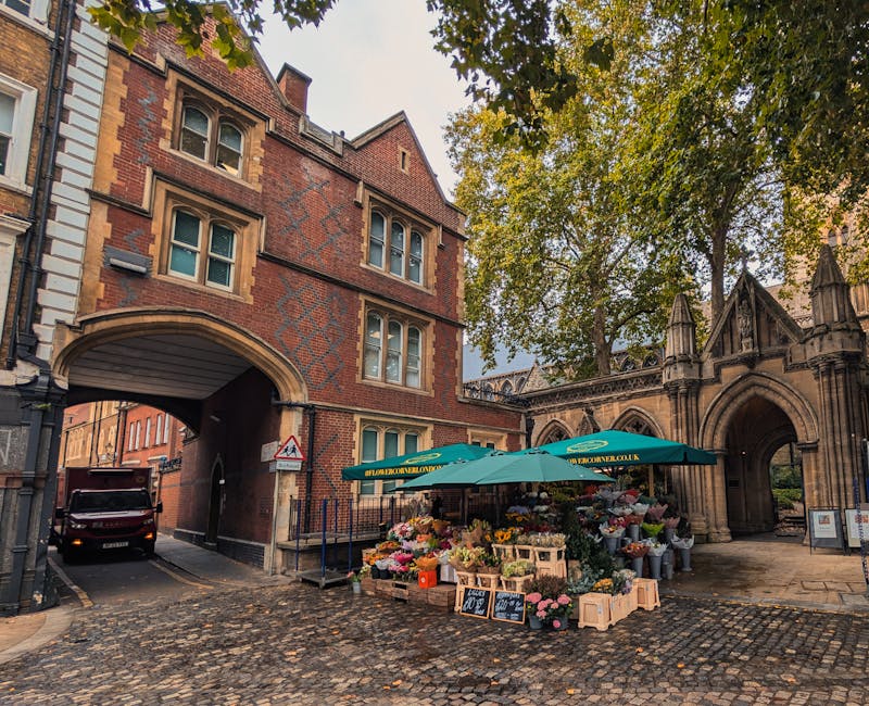 A vibrant flower stall set up outdoors near Brunswick Park Primary School, featuring an assortment of fresh flowers including pink roses, yellow tulips, white lilies, and mixed seasonal blooms arrange
